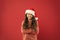 So pleased. time for christmas holiday. small girl in santa hat. cheerful child red background. winter kid fashion