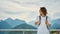 Pleased tourist female with backpack standing in front of mountain top with cloudy sky