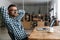 Pleased unshaven man in eyeglasses resting while working with laptop