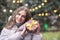 Pleased woman holding girt box at the street with Christmas decoration during the snowfall