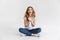 Pleased woman in t-shirt sitting on floor with arms together