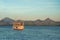 Pleasure boat floating on the ocean. In the background, a chain of mountains