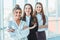 With pleasure, three business women cross their arms, looking at the camera. Dressed in white blouses copy space