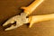 Pliers with orange handles on wooden background. working tool