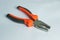 A pliers with rubber orange and dark grey handles