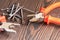 Pliers, side cutters, self-tapping screws on a wooden background, close-up, selective focus