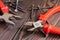 Pliers, side cutters, self-tapping screws on a wooden background, close-up, selective focus