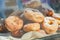 Plile of fresh fried donuts covered with sugar powder on a parchment, sweets in cafe window shop