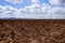 Plough plowed brown clay field blue sky horizon