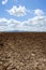 Plough plowed brown clay field blue sky horizon