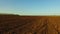 Ploughed field and blue the sky steadicam motion agriculture. Abstract perspective view to dark wide wet soil ways