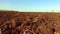 Ploughed field and blue sky steadicam motion agriculture. Abstract perspective view to dark wide wet soil ways, trails