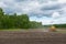 Ploughing tractor working on field, preparing soil for sowing with seedbed cultivator. Agricultural machinery, farming equipment