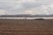 Plowed field against the background of clouds and sunbeams. Spring cleaning of the land, preparation for planting crops