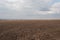 plowed field against the background of clouds and sunbeams. Spring cleaning of the land, preparation for planting crops