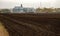 A plowed field in front of the elevator. Grain warehouse.