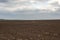 Plowed field landscape minimalistic against the backdrop of the cloudy sky. Spring 2021