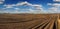 plowed field prepared for sowing and a line of rows, beautiful blue sky with clouds
