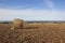 Plowed field with round hay bale