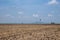 Plowed field in spring time with blue sky. Plowed ground, with brown stones and loose soil .