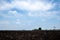 Plowed field in spring time with blue sky. Plowed ground, with brown stones and loose soil .