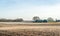 Plowed fields with a farm in the background