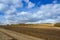 Plows a field,black ground plowed, fields on the background of the sky with clouds