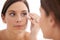 Plucking, eyebrow and woman in mirror with beauty, tweezers and self care in bathroom. Makeup, routine and girl with