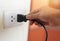 Plug in wall with hand and black power cord cable - Unplug or plugged in concept socket on electric plug on wall