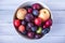 Plum and apples in bowl on a wooden table top view