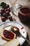 Plum jam in glass jar, with bread on white plate and scattered plums on wooden table, home made plum jam for breakfast concept