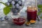 Plum jam in a jar. In the background there are plums. Tkemali sauce. Preparing for winter. Light background.