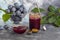 Plum jam in a jar. In the background there are plums. Tkemali sauce. Preparing for winter. Light background.