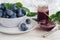 Plum jam in a jar. In the background there are plums. Tkemali sauce. Preparing for winter. Light background.