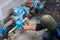 A plumber with balaclava works on an outdoor pipe