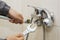 Plumber hands fixing water tap with spanner