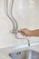 Plumber hands unscrew kitchen faucet vertical view