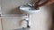 Plumber installs single-lever water faucet on sink in toilet.