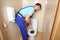 Plumber repairing toilet with hand plunger