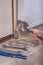 Plumber`s hand holds the adjustable wrench and puts it on the valve at the radiator. Flat keys and tow are on the floor. In th