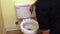 Plumber`s hand repairing toilet seat
