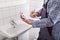 Plumber standing in front of washbasin writing on clipboard