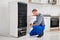 Plumber Writing On Clipboard In Front Of Refrigerator