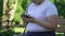 Plump girl sitting in park scrolling pages on smartphone, chatting with friends