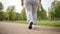 Plump man in athletic attire running along asphalt path in park on sunny day with clear weather