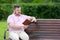 A plump man is reading a book on the bench.