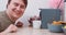 Plump man waits to take cup out of coffee maker at table