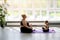 Plump mother and a fragile, thin daughter are doing yoga at home