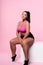 plump mulatto woman sitting on pink background