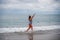 A plump woman in a bathing suit enters the water during the surf. Alone on the beach, Gray sky in the clouds, swimming